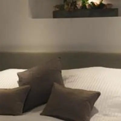 a bed with brown pillows on it with a white bed at The Rooms Lytham in Lytham St Annes