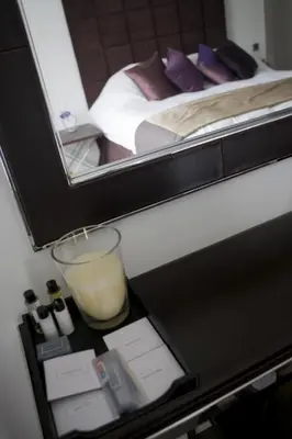 a bedroom with a bed with a mirror and a candle at The Rooms Lytham in Lytham St Annes