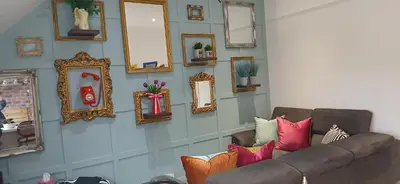a living room with a couch and a wall of mirrors at Seaside Apartment in Moreton