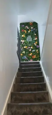 a stairway with a flower rug on the wall at Seaside Apartment in Moreton