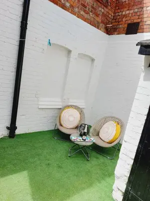 a patio with two chairs and a table on the grass at Seaside Apartment in Moreton