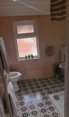 a bathroom with a toilet and a window at Seaside Apartment in Moreton