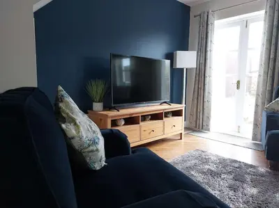 a living room with a flat screen tv on a wooden stand at 2 Bed Cottage in Peaceful South Lakes Village in Cark