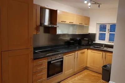 a kitchen with wooden cabinets and black counter tops at 2 Bed Cottage in Peaceful South Lakes Village in Cark