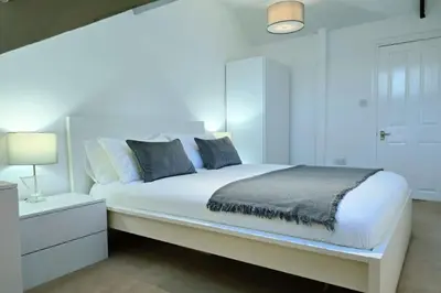 a white bedroom with a large bed and a nightstand at Stylish City Centre Apartment with Parking in Preston