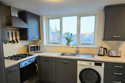 a kitchen with a sink and a stove and windows at Stylish City Centre Apartment with Parking in Preston