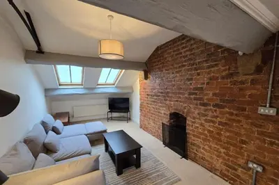 a living room with a couch and a brick wall at Stylish City Centre Apartment with Parking in Preston