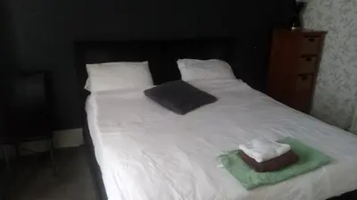 a bed with white sheets and two towels on it at The New Macleods Guest House in Blackpool