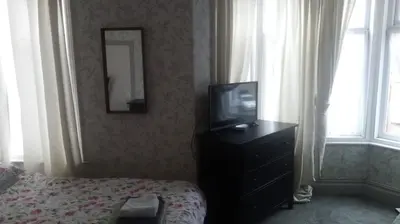 a bedroom with a tv and a dresser with a bed at The New Macleods Guest House in Blackpool