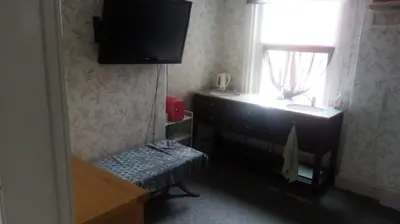 a room with a tv on the wall and a window at The New Macleods Guest House in Blackpool