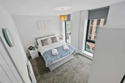 a bedroom with a bed with pillows and a window at Baltic Triangle Apartment in Liverpool