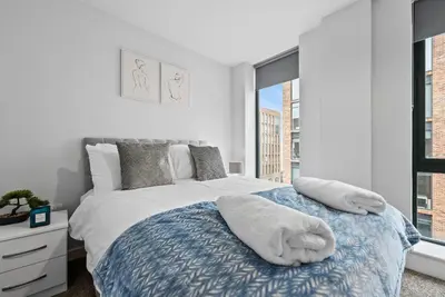a white bedroom with a bed with towels on it at Baltic Triangle Apartment in Liverpool