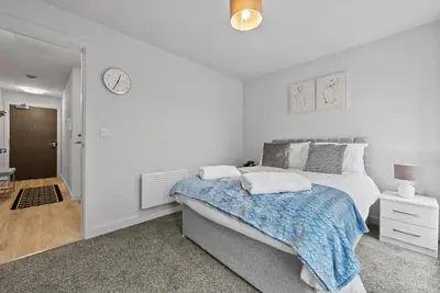 a white bedroom with a bed and a clock on the wall at Baltic Triangle Apartment in Liverpool