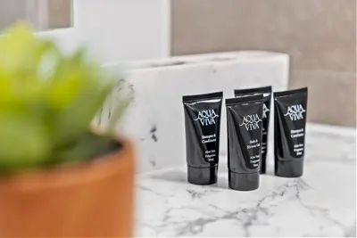 a row of four black tubes of hair products on a counter at Baltic Triangle Apartment in Liverpool