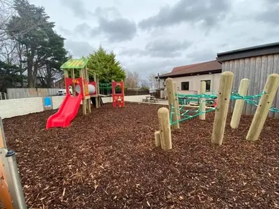 a playground with a red and green slide at Mags den in Morecambe