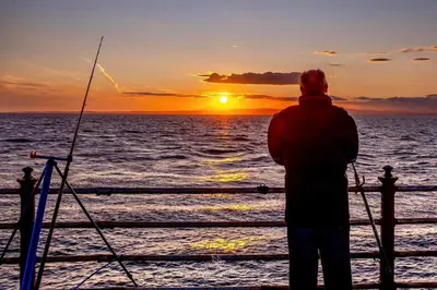 a man standing on a pier watching the sunset at Mags den in Morecambe