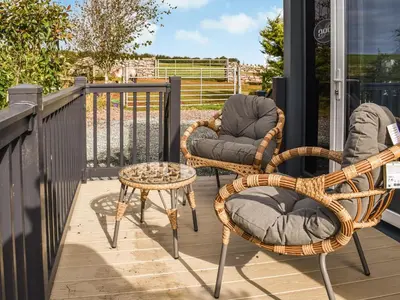 two wicker chairs and a table on a balcony at The Lodge Pod in Barrow in Furness