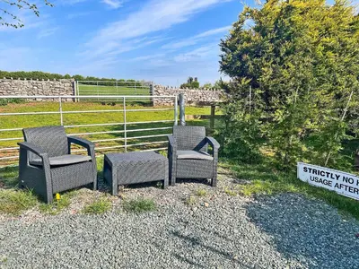 two chairs and a sign in front of a field at The Lodge Pod in Barrow in Furness
