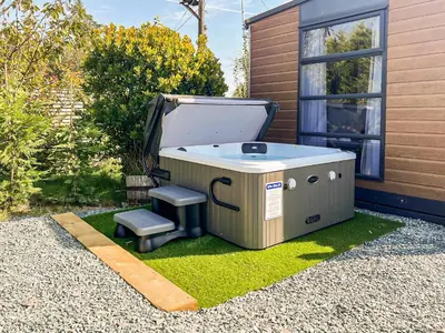 a hot tub sitting on the grass next to a house at The Lodge Pod in Barrow in Furness