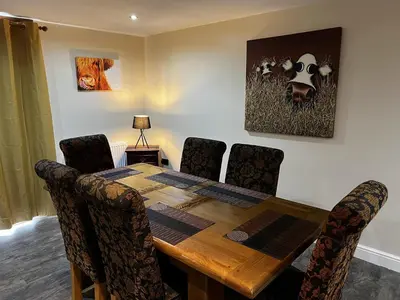 a dining room table with chairs and a cow on the wall at Luxury Country Lodge in Bretherton - Sleeps 4 in Bretherton