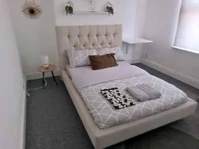 a bedroom with a white bed with a large headboard at Noble Prestige Place in Liverpool