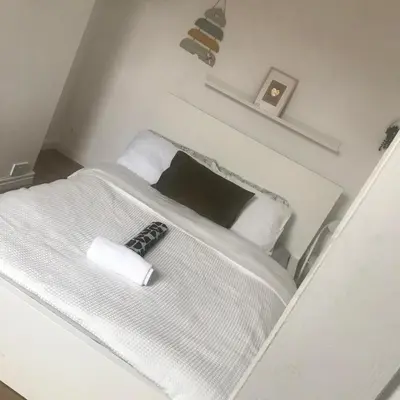 a white bed with a remote control on top of it at Noble Prestige Place in Liverpool