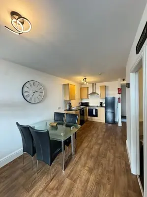 a living room with a table and a clock on the wall at Subway Apartments in Blackpool