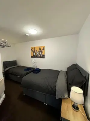 a bedroom with two beds and a table with a lamp at Subway Apartments in Blackpool