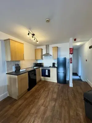 a kitchen with a black refrigerator and wooden floors at Subway Apartments in Blackpool