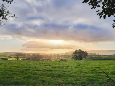 a field of green grass with the sun in the background at The Old Loft in Slaidburn