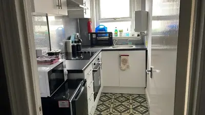 a kitchen with white cabinets and a black counter top at Great House 5 Min walk 2 Beach best locations in Blackpool in Blackpool