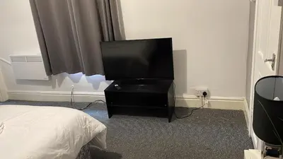a flat screen tv sitting on a stand in a bedroom at Great House 5 Min walk 2 Beach best locations in Blackpool in Blackpool