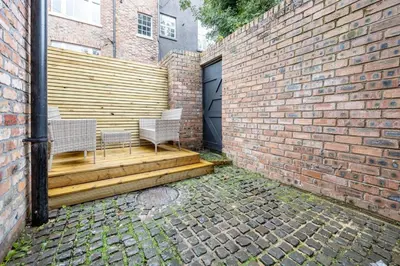 a patio with two chairs and a brick wall at GuestReady - Georgian Quarter retreat with terrace in Liverpool