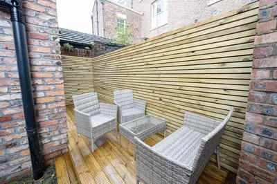 a patio with three chairs and a wooden fence at GuestReady - Georgian Quarter retreat with terrace in Liverpool