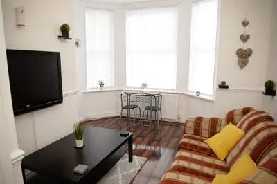 a living room with a couch and a table at Cosy Orrell Park Retreat Near Anfield and Aintree in Liverpool