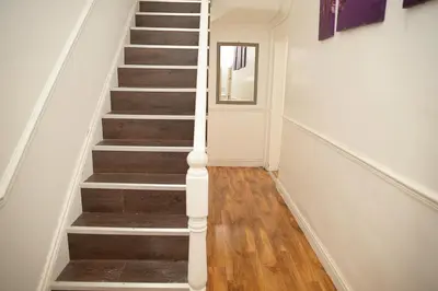 a staircase with white railings and wood flooring at Cosy Orrell Park Retreat Near Anfield and Aintree in Liverpool