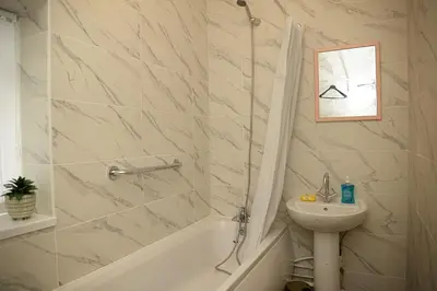 a bathroom with a sink and a toilet and a bath tub at Cosy Orrell Park Retreat Near Anfield and Aintree in Liverpool