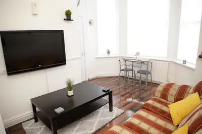a living room with a couch and a table at Cosy Orrell Park Retreat Near Anfield and Aintree in Liverpool