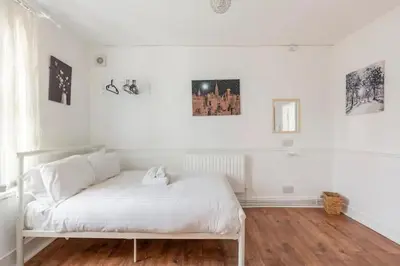a white bed in a room with white walls at Cheerful Maisonette in the heart of Orrell Park in Liverpool
