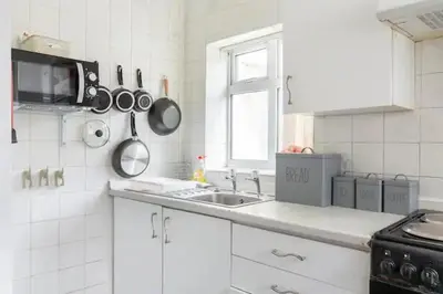a kitchen with a sink and pots and pans on the wall at Cheerful Maisonette in the heart of Orrell Park in Liverpool