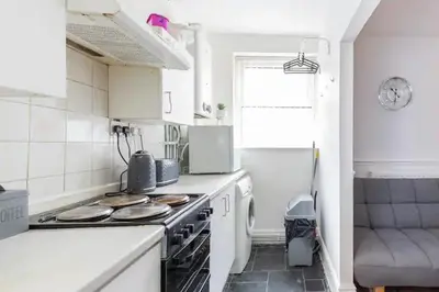 a small white kitchen with a stove top oven at Cheerful Maisonette in the heart of Orrell Park in Liverpool