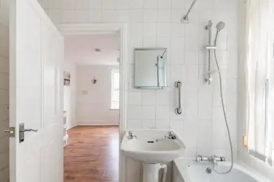 a white bathroom with a sink and a bath tub at Cheerful Maisonette in the heart of Orrell Park in Liverpool