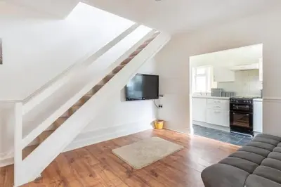 a living room with a staircase with a couch and a tv at Cheerful Maisonette in the heart of Orrell Park in Liverpool