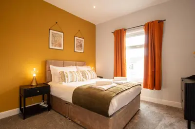 a bedroom with a bed and a window with orange curtains at Britannia Apartments in Liscard Village Wallasey by Rework Accommodation in Wallasey