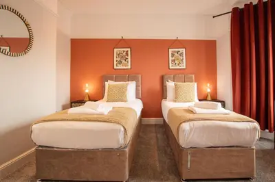 two beds in a room with orange walls at Britannia Apartments in Liscard Village Wallasey by Rework Accommodation in Wallasey