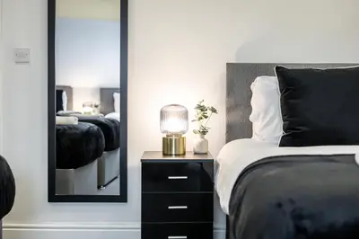 a bedroom with a bed with a lamp and a mirror at Anfield Cosy Stays - Air Host & Stay - Sleeps 14 in Liverpool