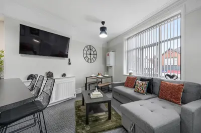 a living room with a couch and a tv at Anfield Cosy Stays - Air Host & Stay - Sleeps 14 in Liverpool