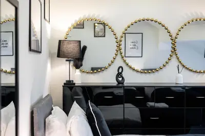 a room with mirrors on the wall and a black dresser at Anfield Cosy Stays - Air Host & Stay - Sleeps 14 in Liverpool