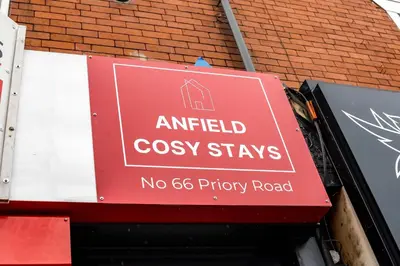 a red sign on the side of a brick building at Anfield Cosy Stays - Air Host & Stay - Sleeps 14 in Liverpool