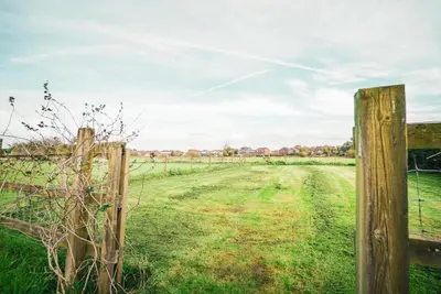 a fence in the middle of a field at The Old Lambing Barn in Longton